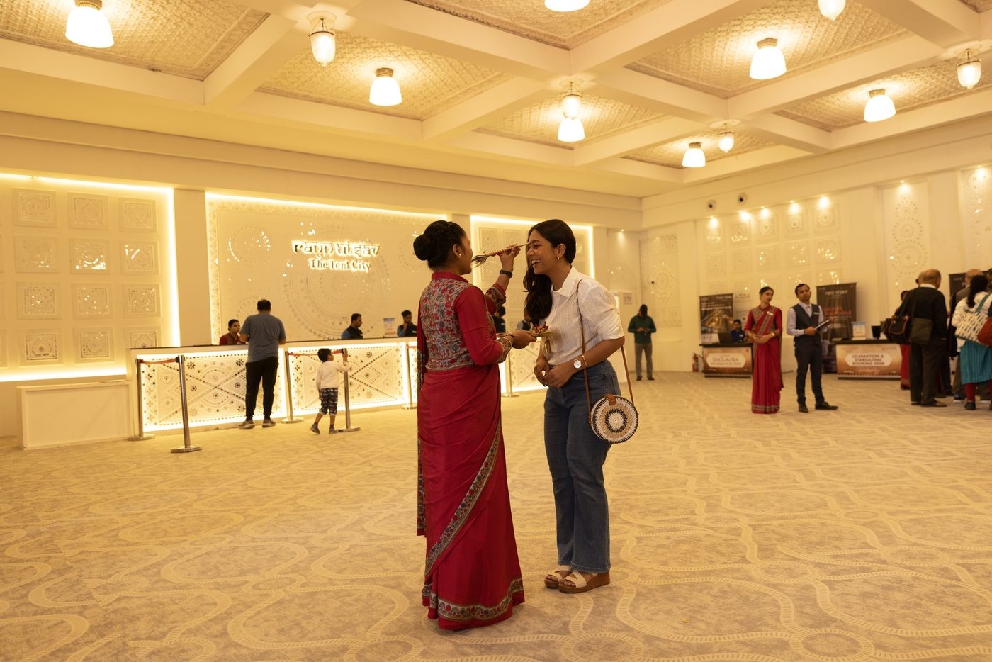 Staff member applying a traditional tilak to a smiling guest at the Rann Utsav Tent City reception